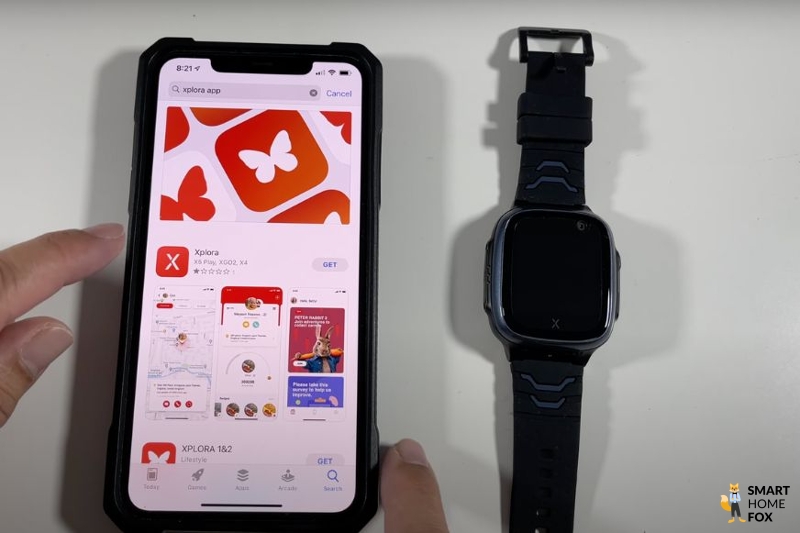 Man sieht die XPLORA X5 Play neben einem Handy auf dem Tisch liegen.